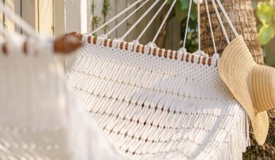 Straw hat hanging on white hammock outdoor. Relaxing summer vaca
